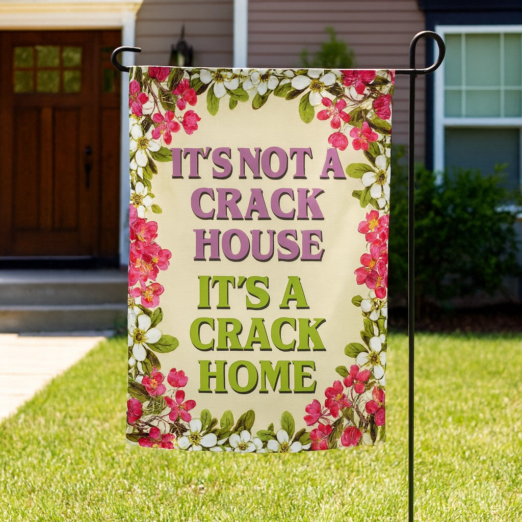 Garden flag with floral border and text 'It's not a crack house, it's a crack home' on a lawn.