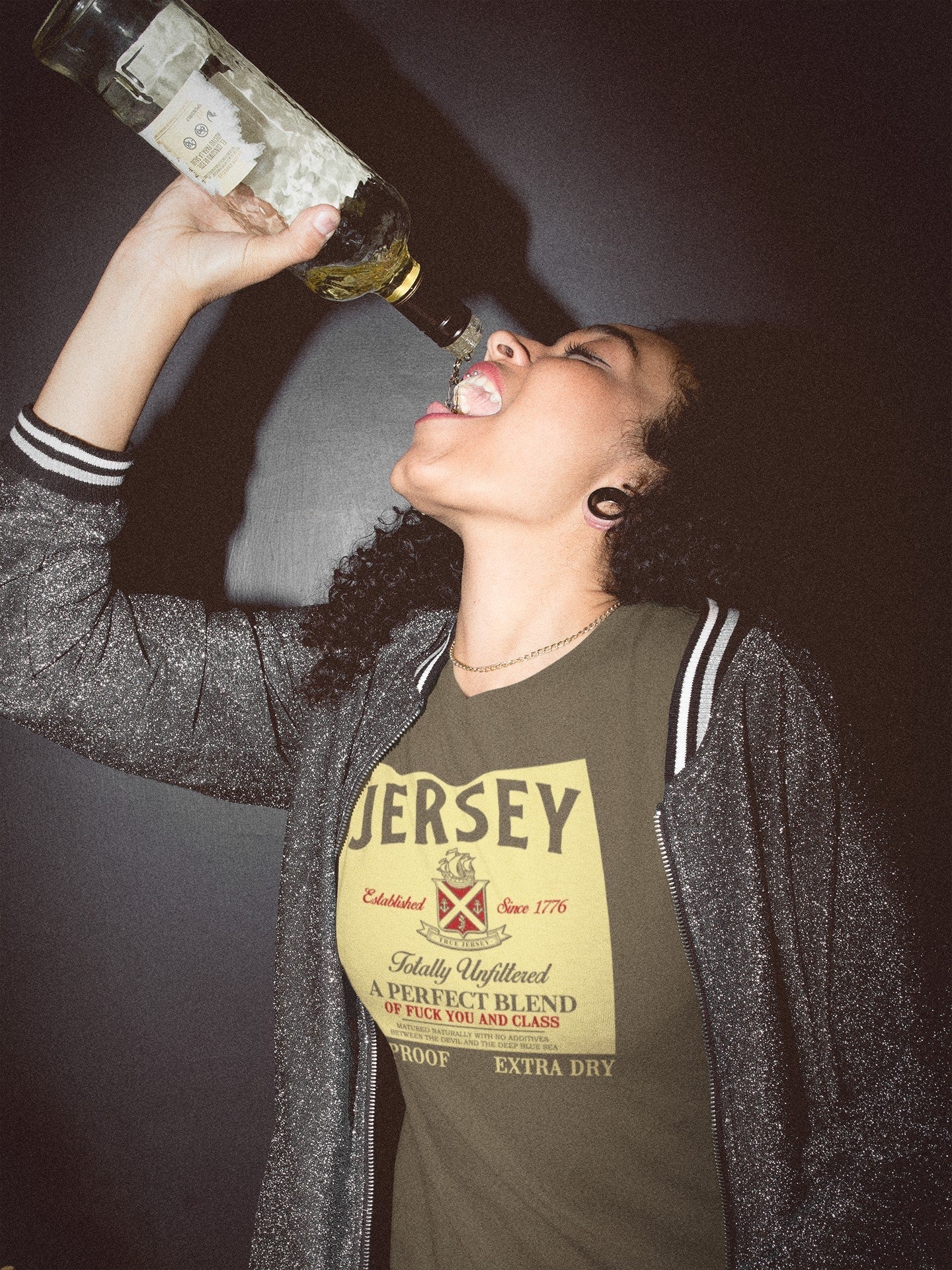 Person wearing a 'Jersey' t-shirt drinking from a bottle against a dark background